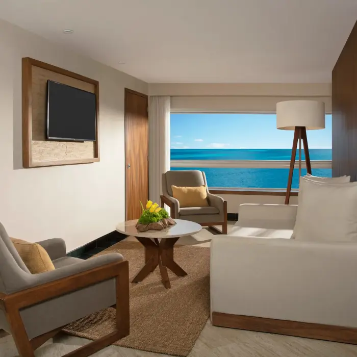 Junior Suite living space with sofa, desk, and TV, overlooking a tropical terrace with private plunge pool.