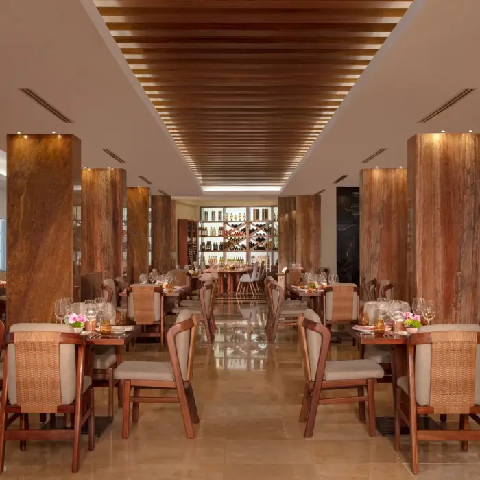 Elegant restaurant interior with polished floors, wood columns, and woven-back chairs arranged in rows.