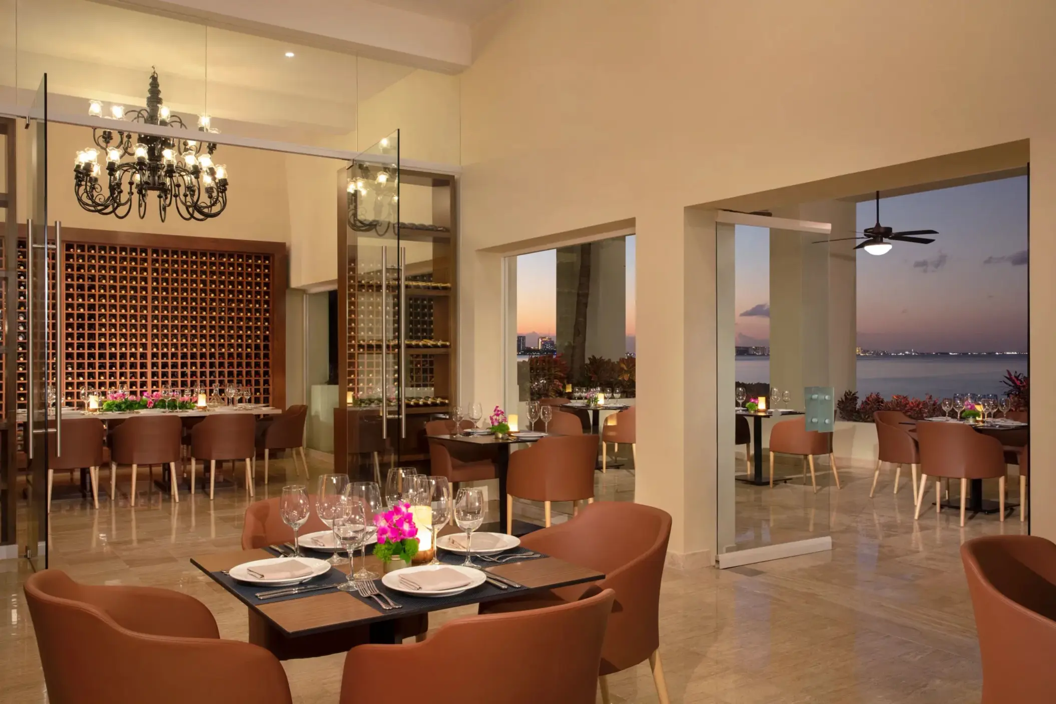 Elegant indoor-outdoor dining space at Portofino restaurant with ocean views and modern chandeliers.