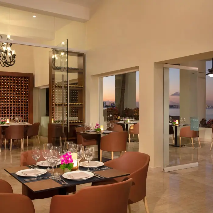 Elegant indoor-outdoor dining space at Portofino restaurant with ocean views and modern chandeliers.
