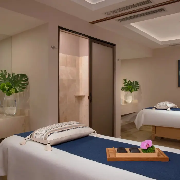 Peaceful spa cabin with twin massage tables, soft lighting, and natural décor elements.