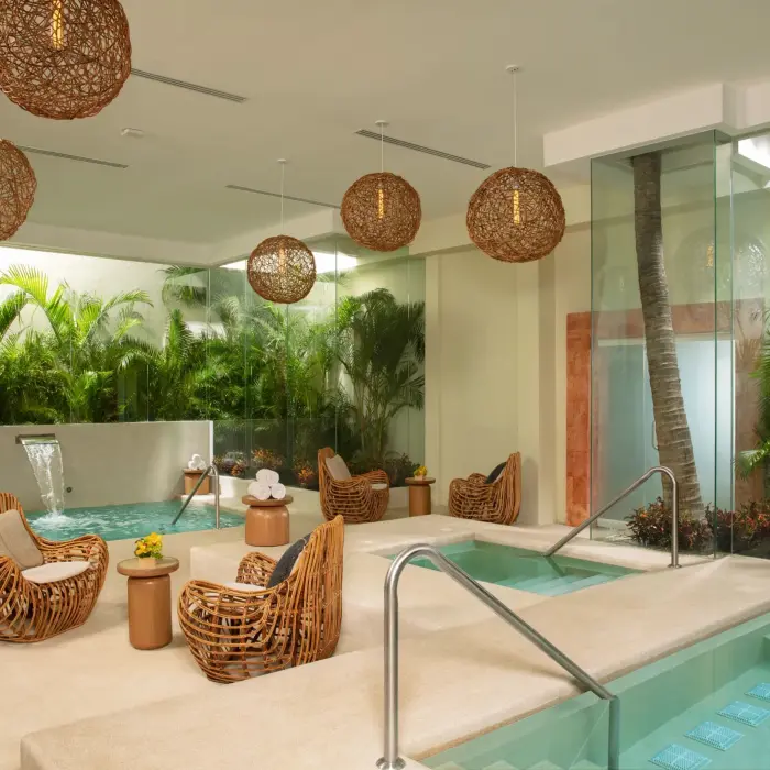 Relaxing hydrotherapy area with wicker lounge chairs, warm lighting, and spa plunge pools.