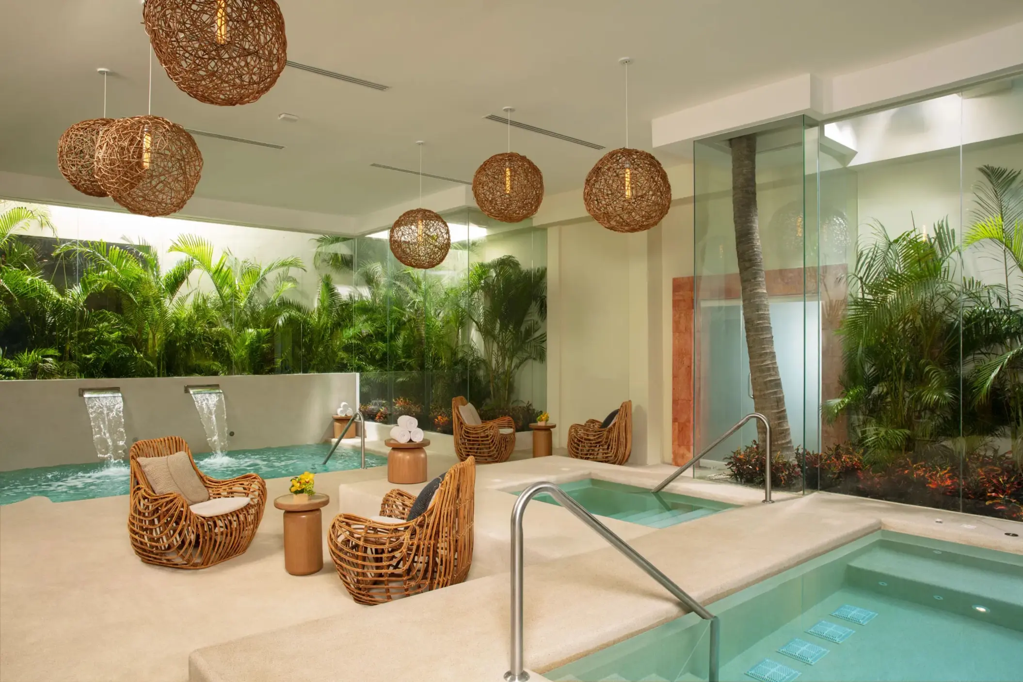 Relaxing hydrotherapy area with wicker lounge chairs, warm lighting, and spa plunge pools.