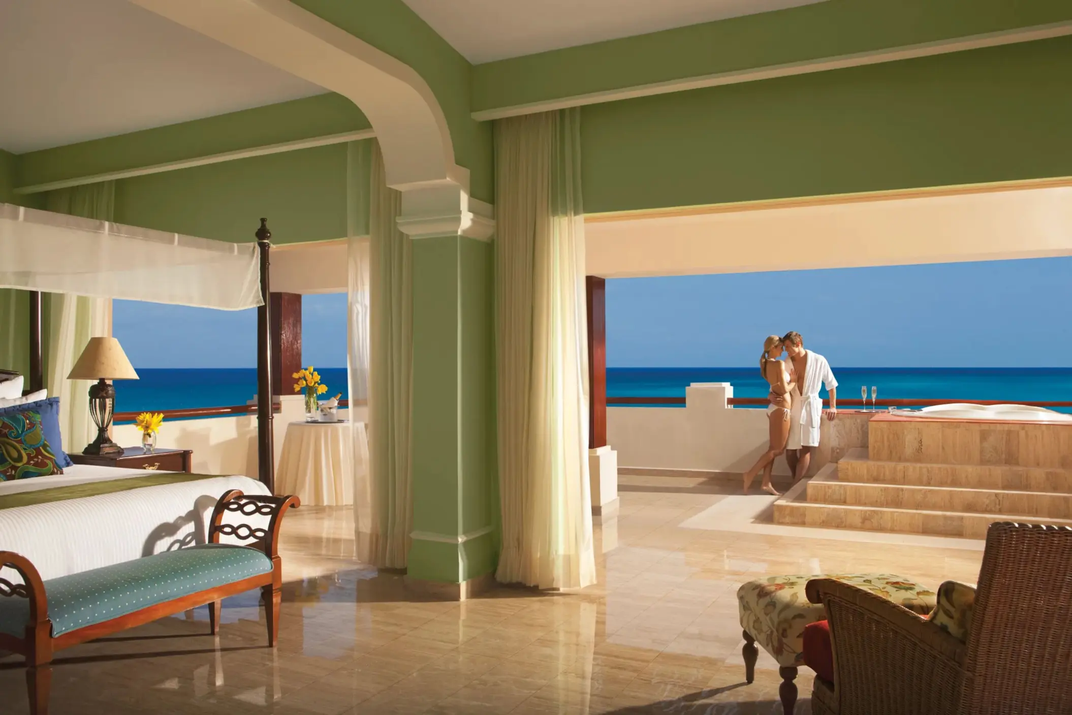 Romantic ocean-view suite with a couple enjoying the hot tub on a private terrace overlooking the sea.