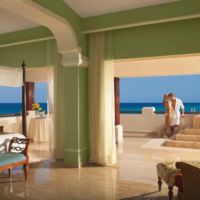Romantic ocean-view suite with a couple enjoying the hot tub on a private terrace overlooking the sea.