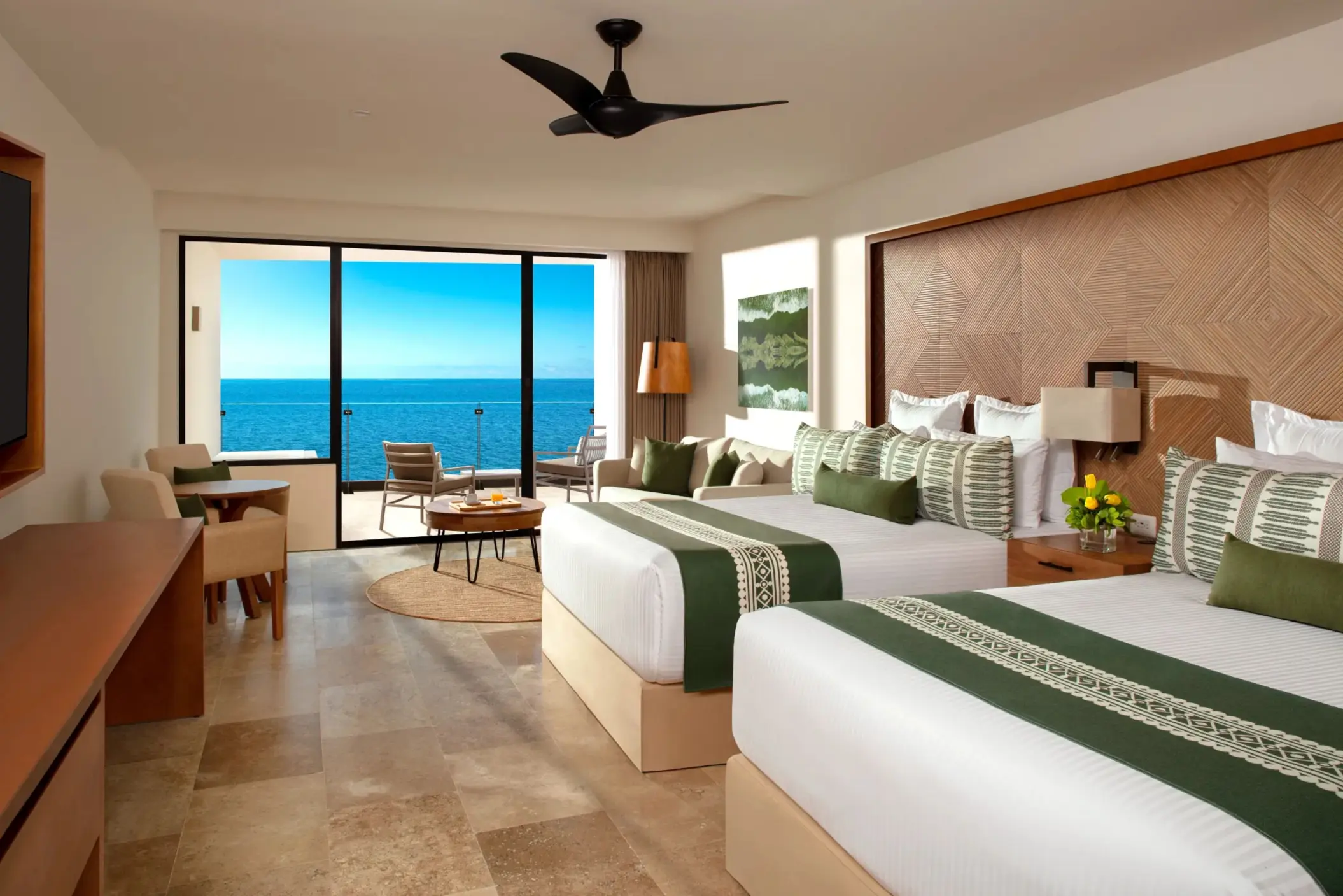 Oceanfront room with two double beds, tropical wood accents, and a balcony overlooking the sea.