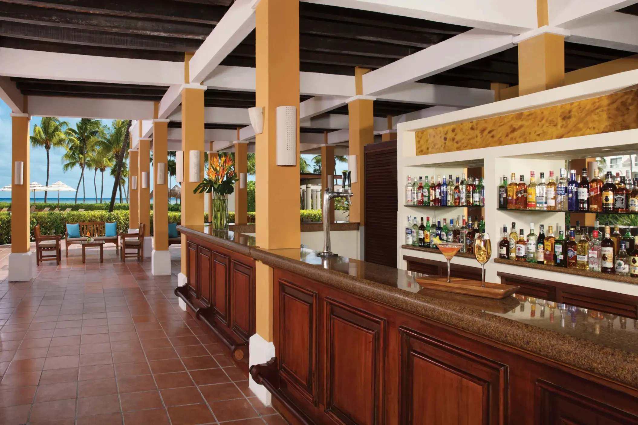 Outdoor Sugar Reef bar with wood and tile decor, tropical cocktails, and ocean views at Dreams Tulum Resort & Spa.