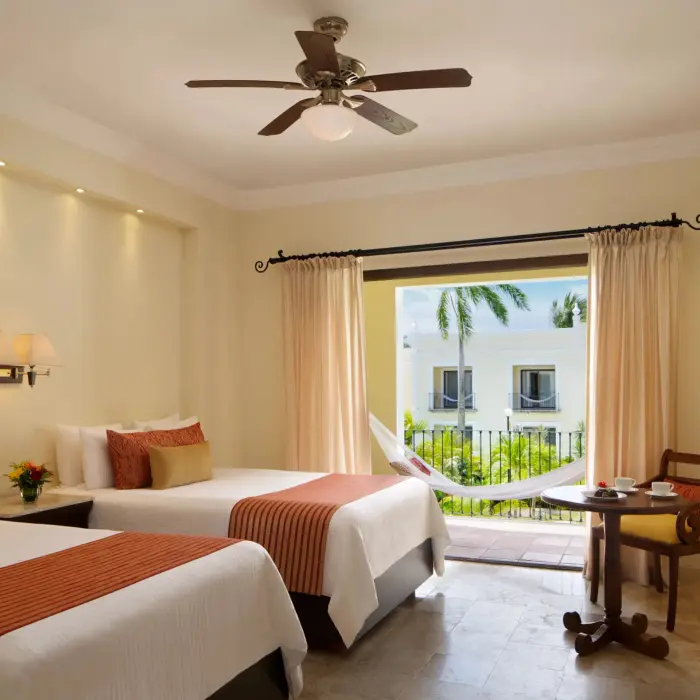 Spacious room with two double beds, tropical garden view, and hammock on the balcony.