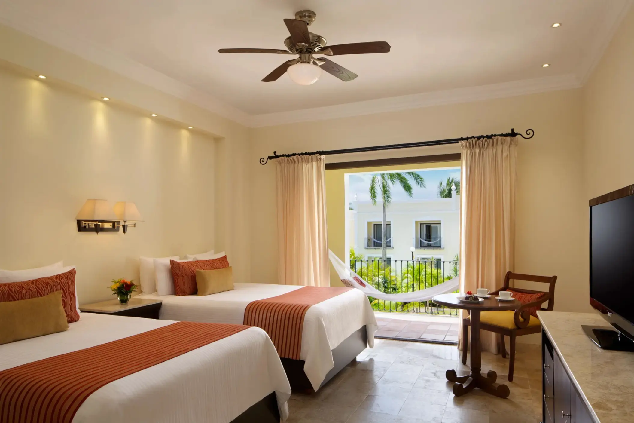 Spacious room with two double beds, tropical garden view, and hammock on the balcony.