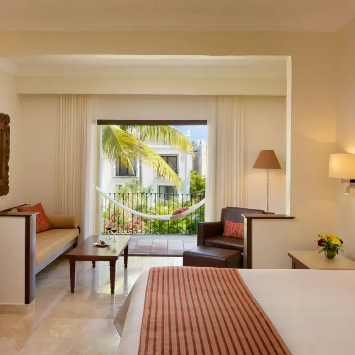Bright and inviting room with king bed, patio seating, and soft lighting.
