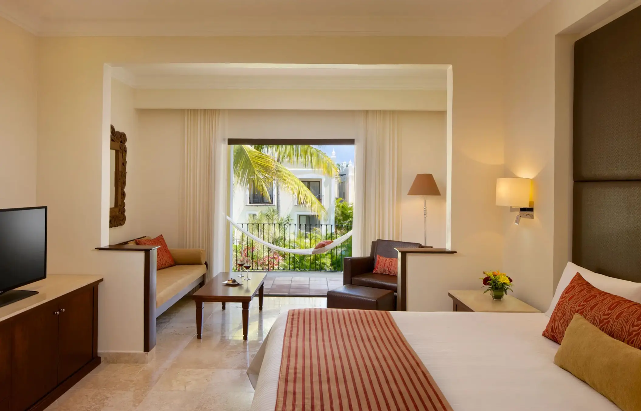 Bright and inviting room with king bed, patio seating, and soft lighting.