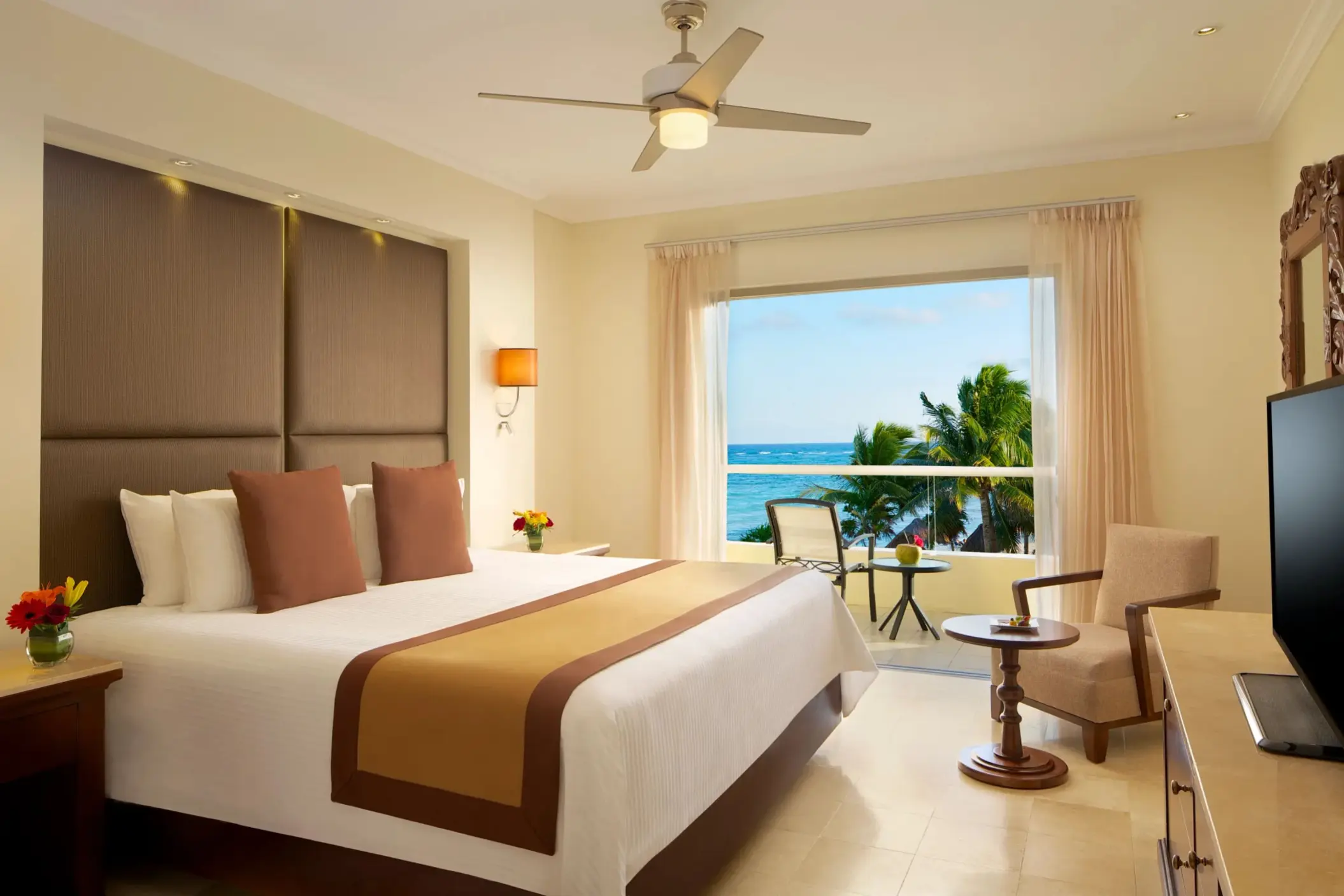 King bed ocean view room with neutral tones, tropical decor, and balcony seating.