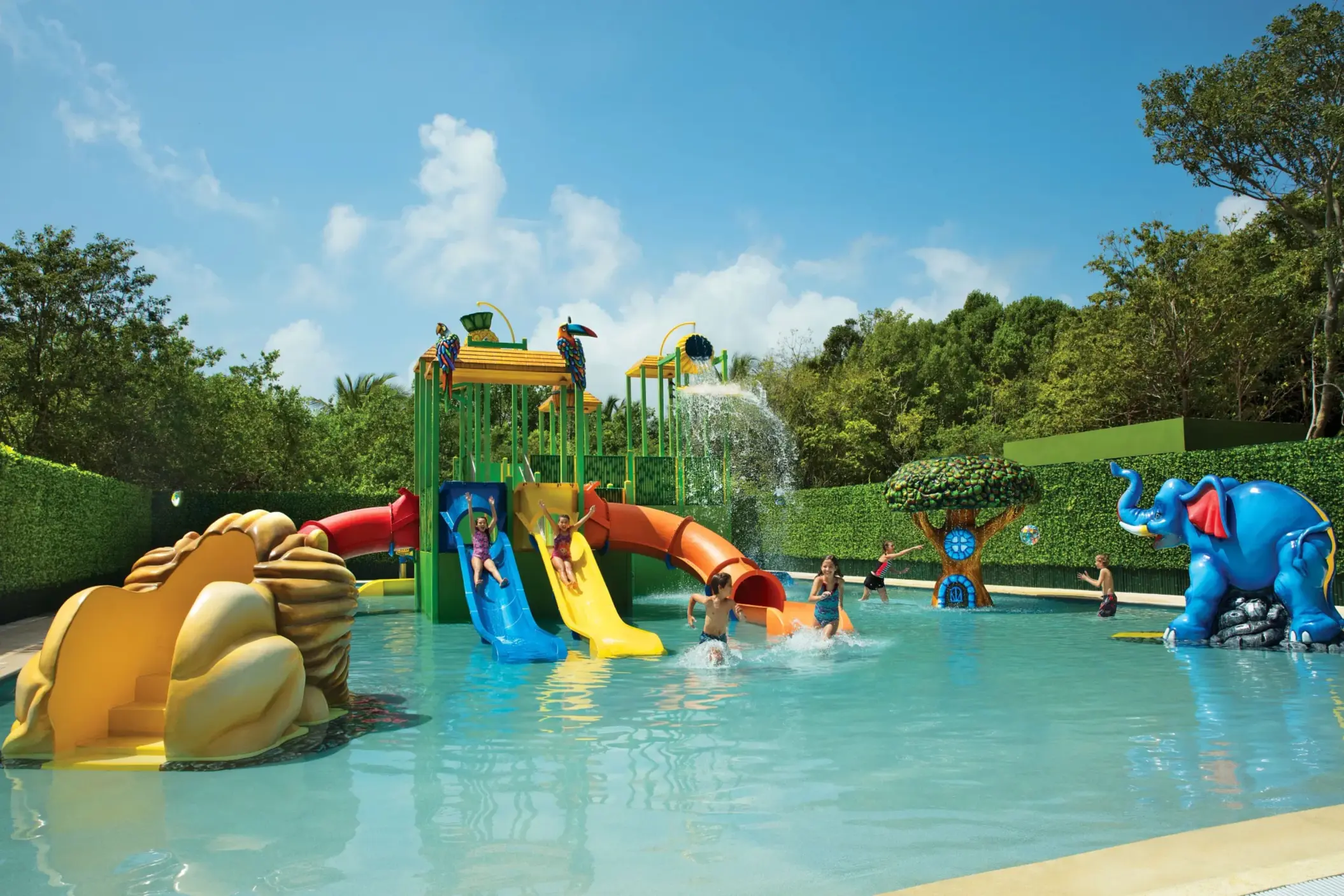 Kids splash zone at Dreams Tulum’s Explorer’s Club with colorful water slides, fountains, and jungle-themed decor.