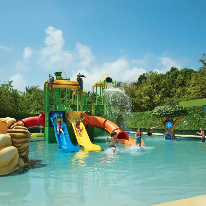 Kids splash zone at Dreams Tulum’s Explorer’s Club with colorful water slides, fountains, and jungle-themed decor.