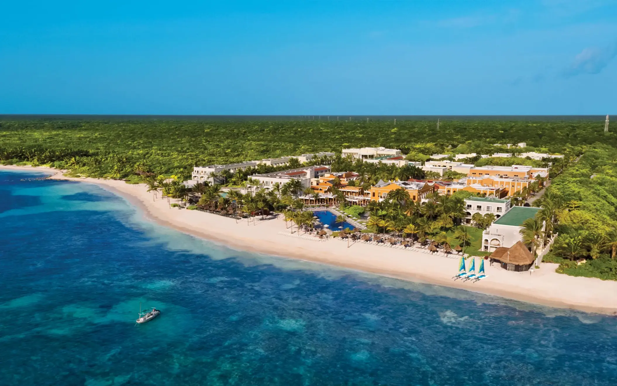 Aerial view of Dreams Tulum Resort & Spa with beach, pools, tropical landscaping, and colorful hacienda-style buildings.