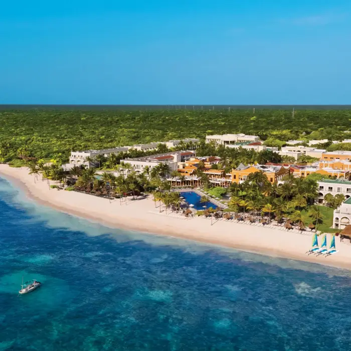 Aerial view of Dreams Tulum Resort & Spa with beach, pools, tropical landscaping, and colorful hacienda-style buildings.