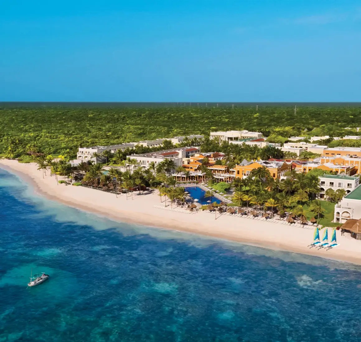 Aerial view of Dreams Tulum Resort & Spa with beach, pools, tropical landscaping, and colorful hacienda-style buildings.
