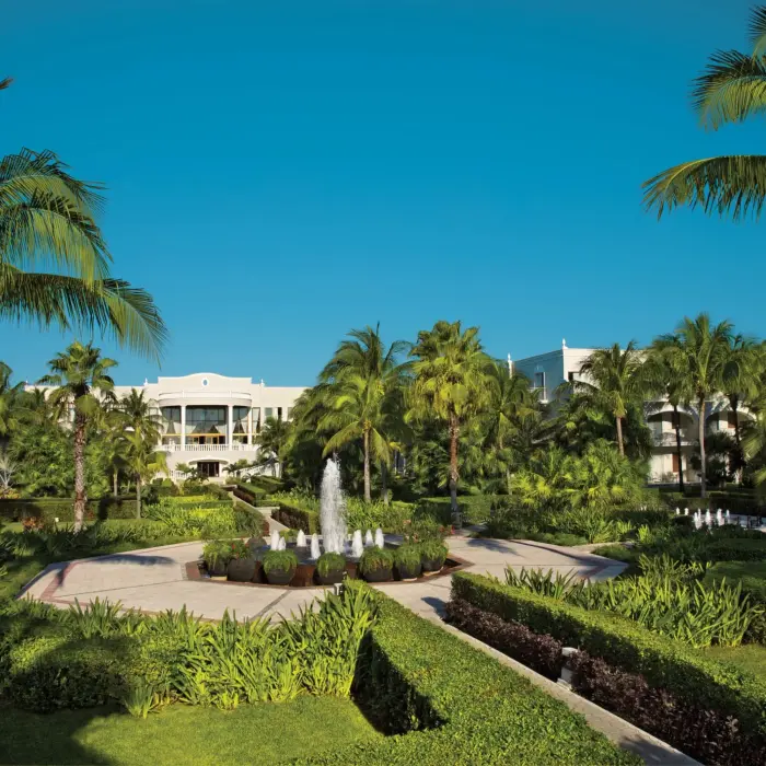 Lush tropical gardens with palm trees, fountains, and manicured walkways at Dreams Tulum Resort & Spa.