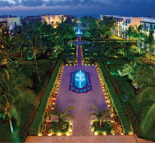 Dreams Tulum’s gardens illuminated at night with glowing fountains and palm trees creating a tropical ambiance.