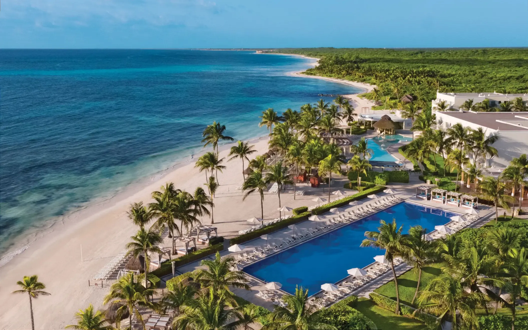 Aerial view of beachfront and multiple pools at Dreams Tulum, surrounded by palms and Caribbean coastline.