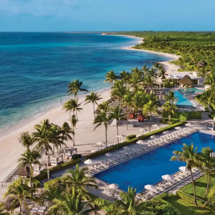 Aerial view of beachfront and multiple pools at Dreams Tulum, surrounded by palms and Caribbean coastline.