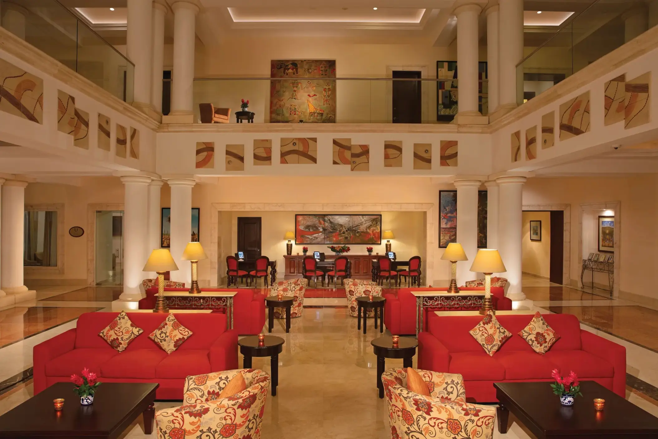 Spacious lobby with red sofas, classic columns, and warm lighting in a colonial-style setting.
