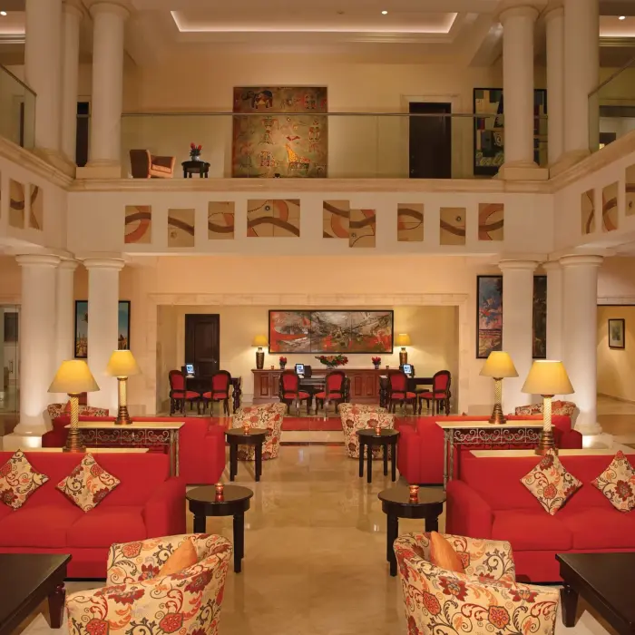 Spacious lobby with red sofas, classic columns, and warm lighting in a colonial-style setting.