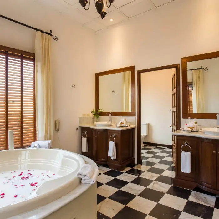 Classic bathroom with a large soaking tub filled with rose petals, double vanity, and checkered tile flooring.
