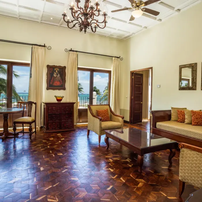 Colonial-inspired living room with ocean views, carved wood furniture, chandeliers, and balcony access.