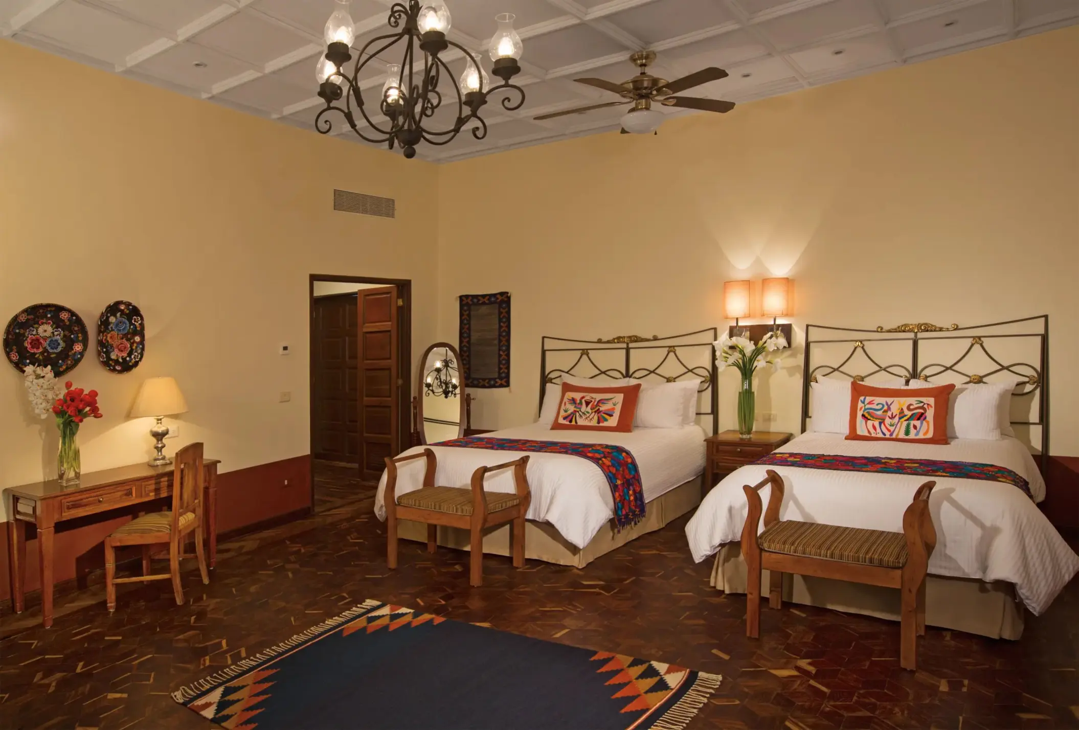 Double bed suite with rustic charm, artisanal embroidered pillows, and decorative wall plates for a cultural touch.