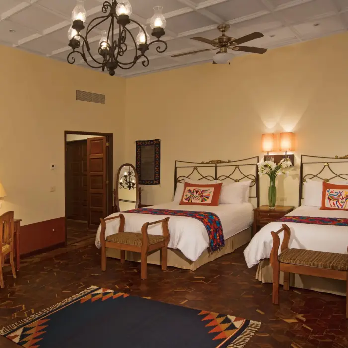 Double bed suite with rustic charm, artisanal embroidered pillows, and decorative wall plates for a cultural touch.