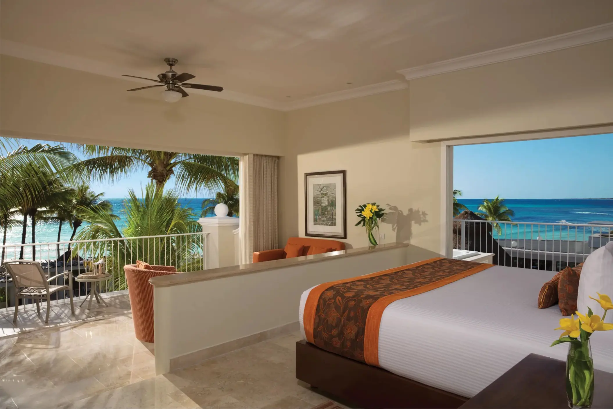 Spacious oceanfront room with king bed, seating area, and large balcony overlooking turquoise Caribbean waters.