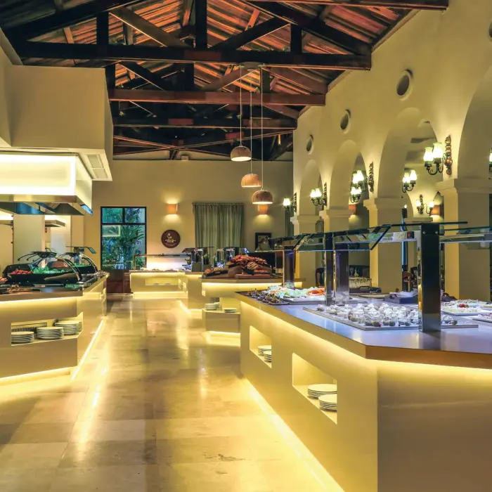 Modern buffet setup with glowing counters, high ceilings, and a wide variety of international cuisine stations.