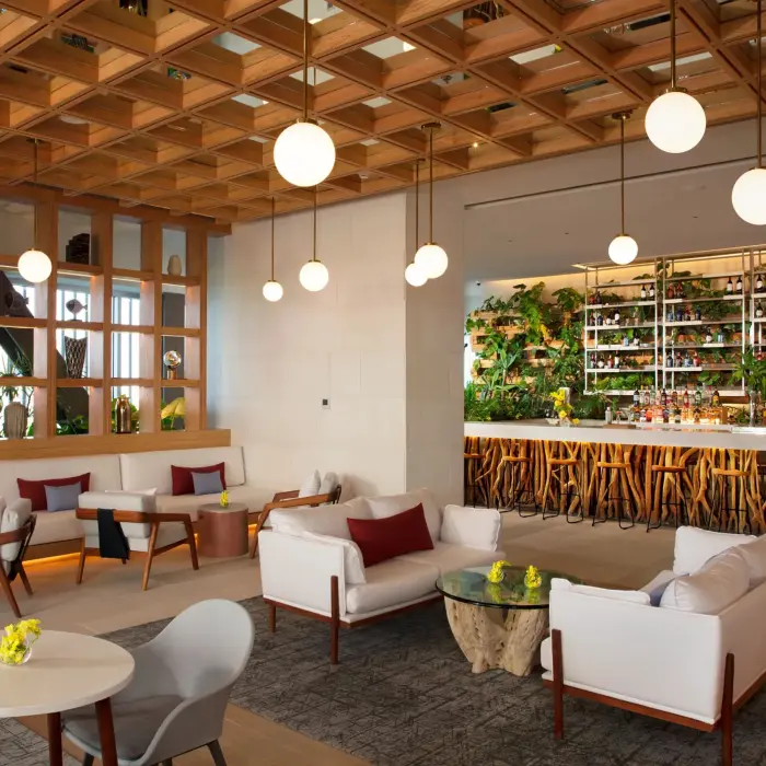 Stylish Rendezvous lobby bar featuring lush decor, natural wood accents, and indoor garden elements.