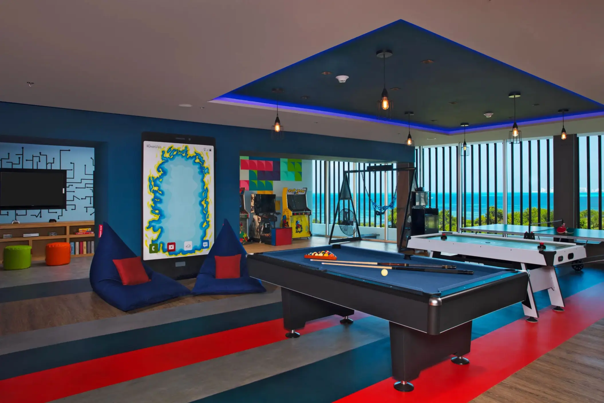 Modern teen lounge with bean bags, game tables, and ocean views at the Core Zone.