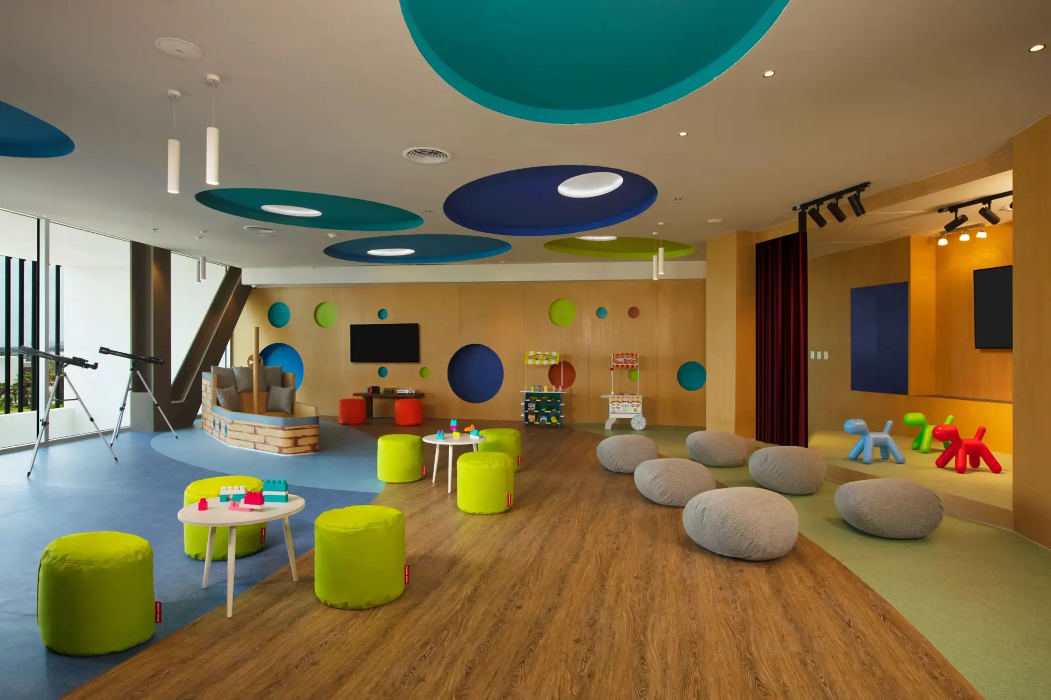Colorful Explorer’s Club indoor play area with games, soft seating, and telescopes for kids.