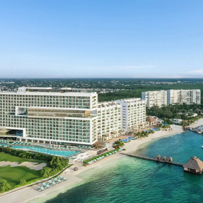 Aerial view showcasing golf course, beachfront, and modern resort layout.