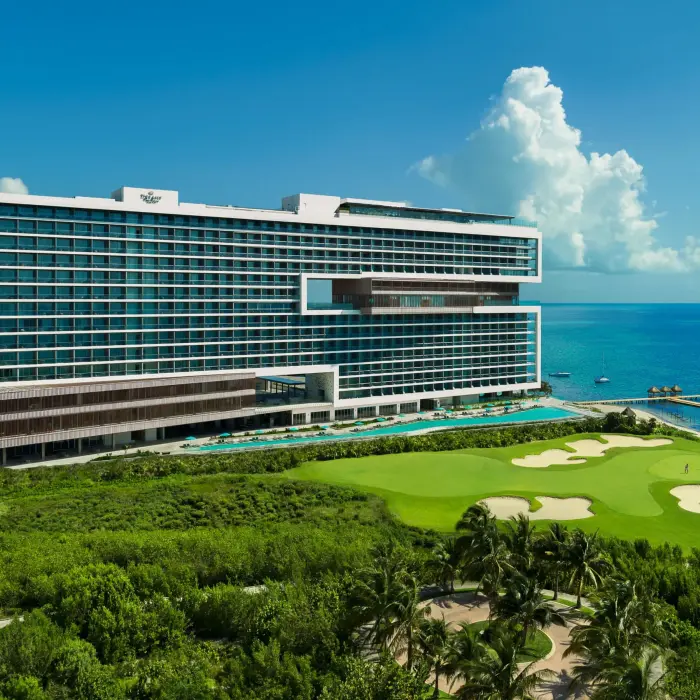 Aerial view with lush greenery, golf course, and beachfront access.