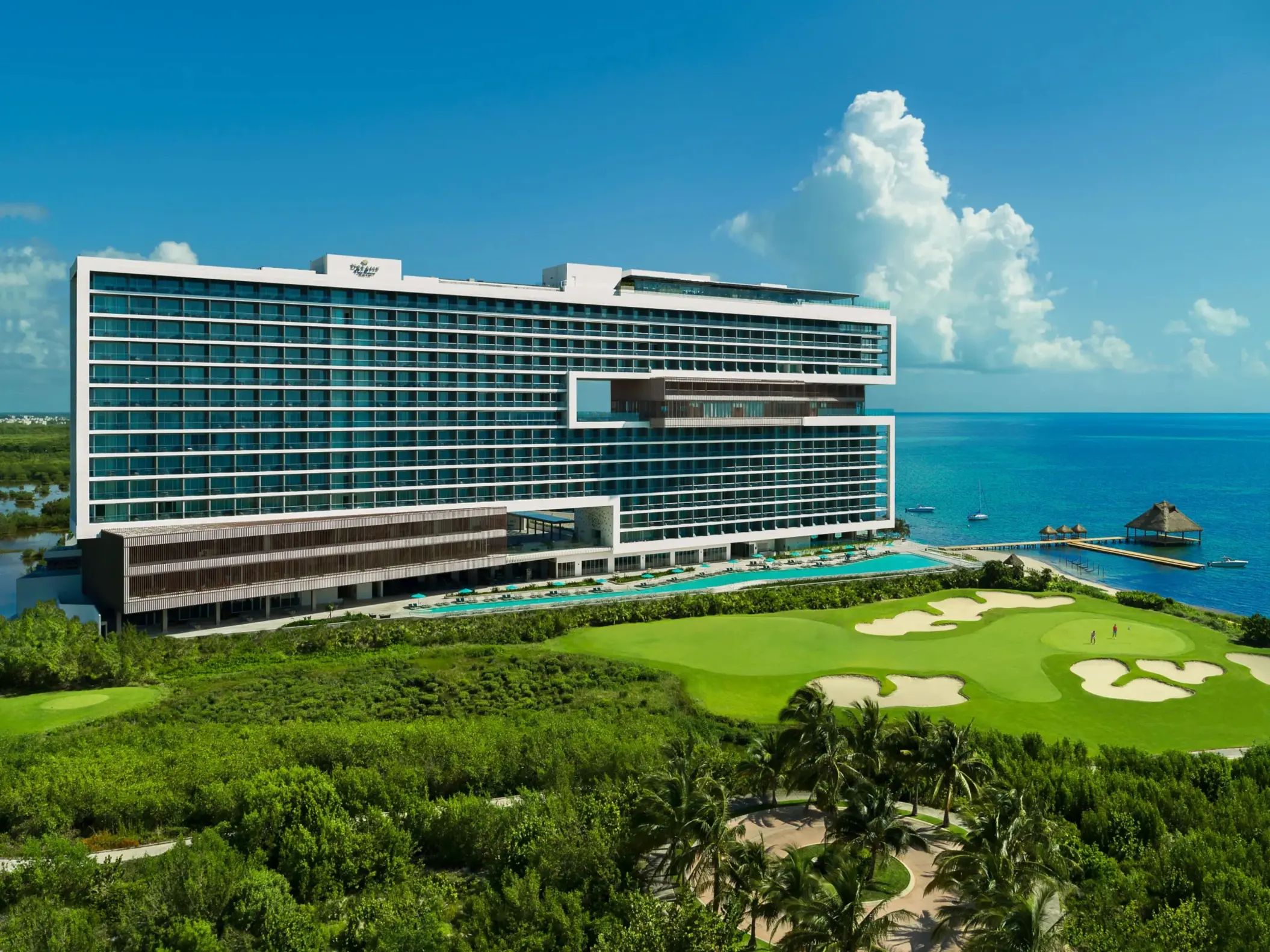 Aerial view with lush greenery, golf course, and beachfront access.