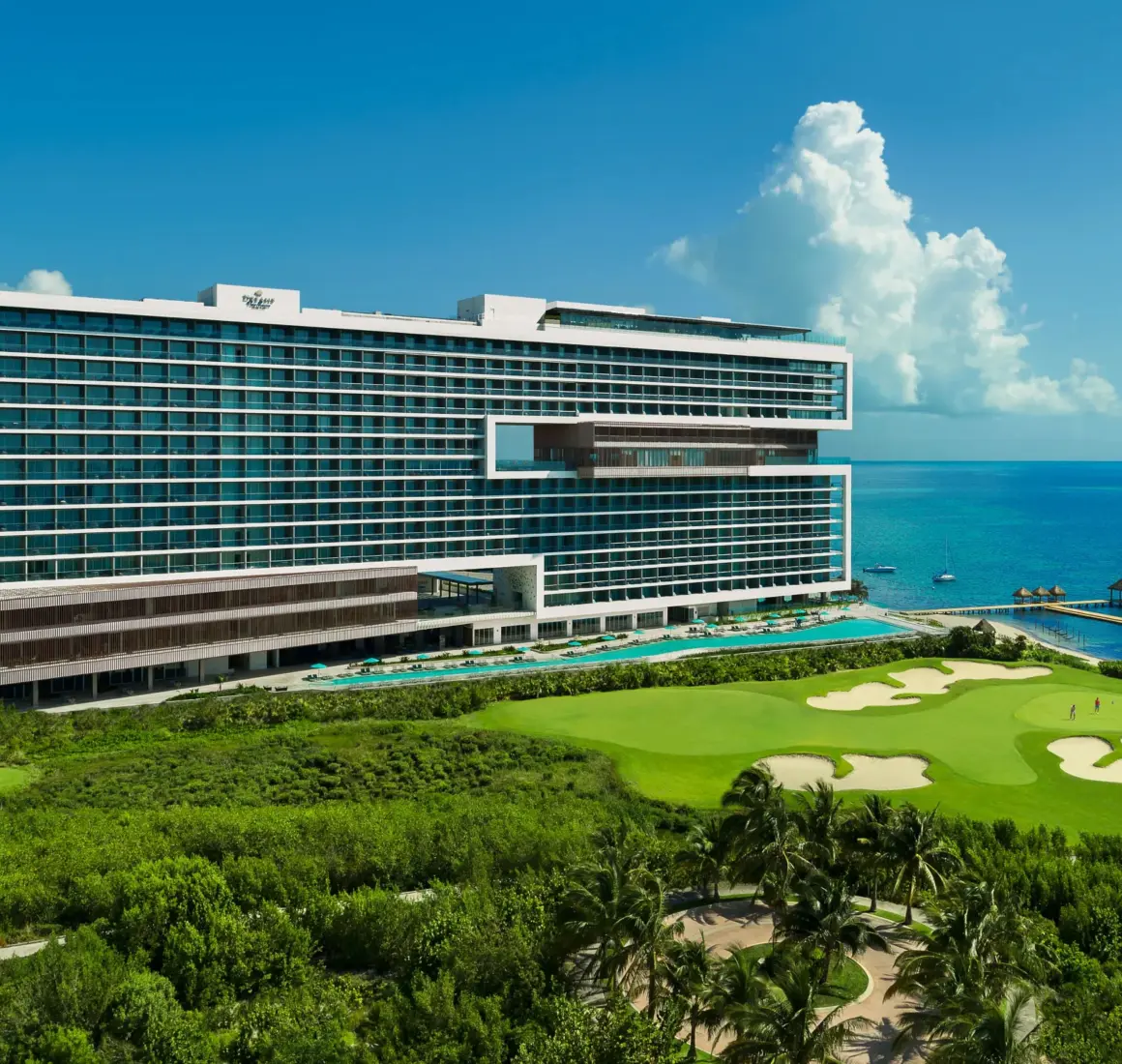 Aerial view with lush greenery, golf course, and beachfront access.