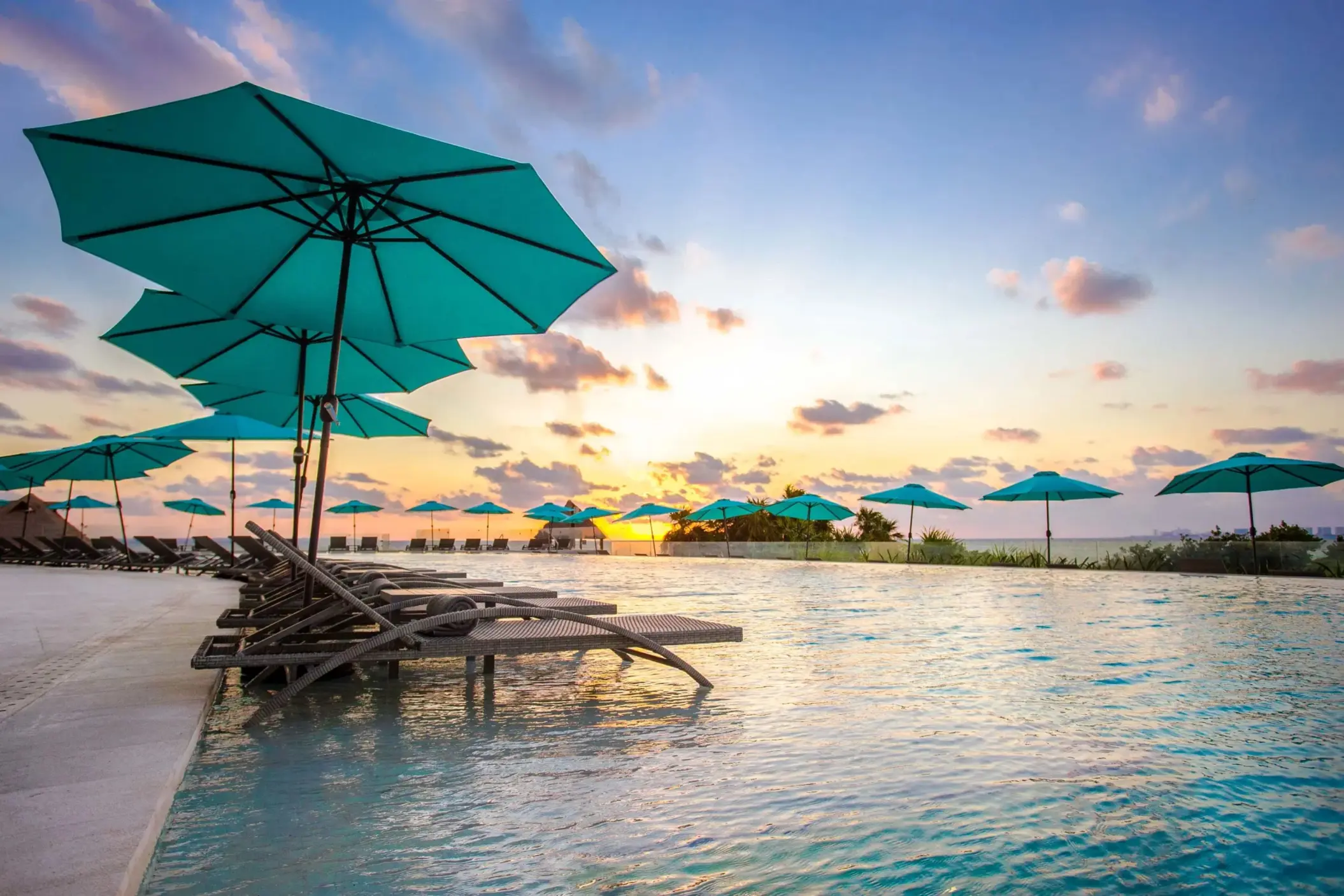 Lounge chairs beside the infinity pool with wooden canopy and endless ocean views.