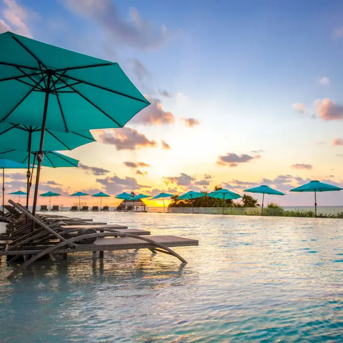 Lounge chairs beside the infinity pool with wooden canopy and endless ocean views.