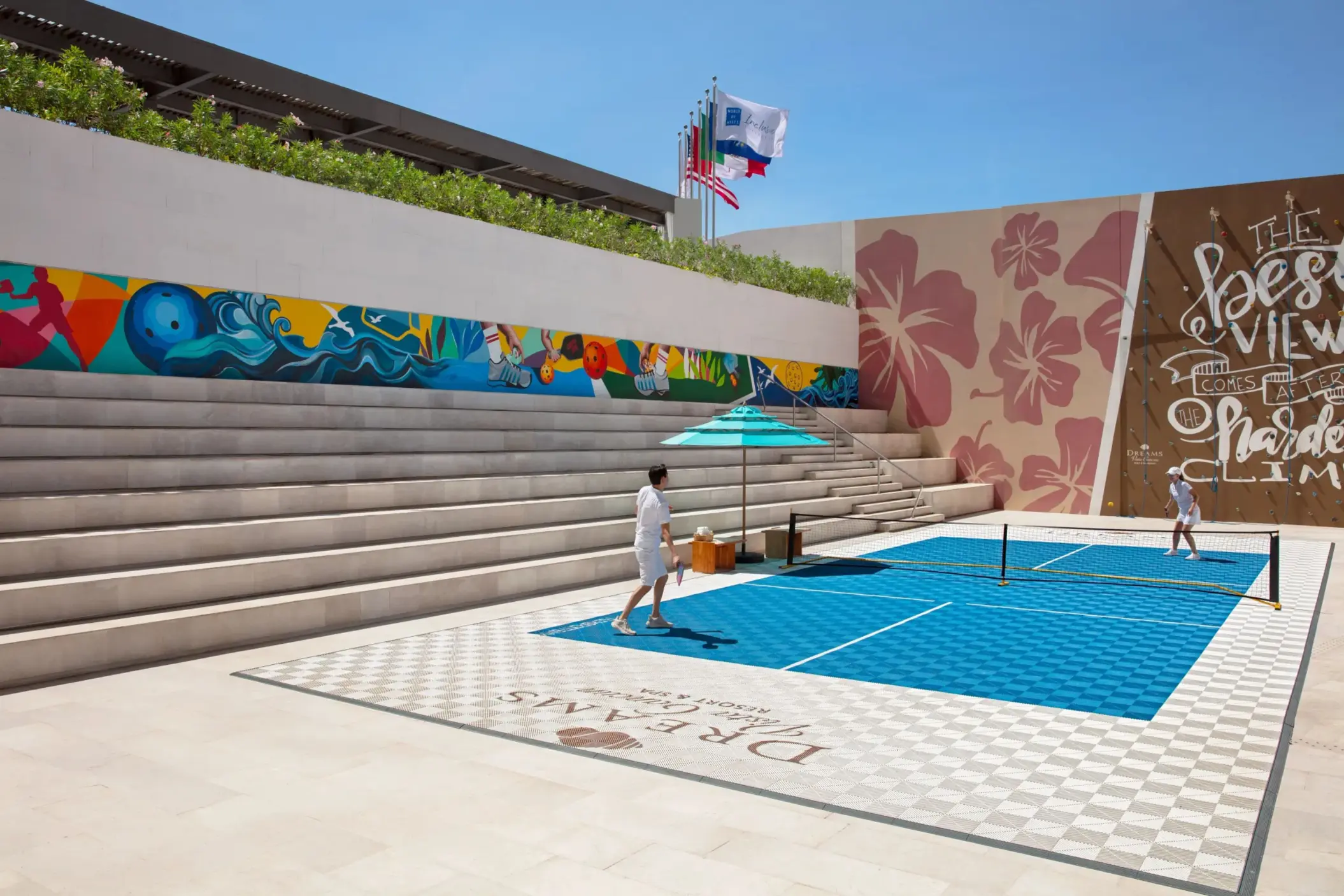Outdoor pickleball court surrounded by stadium seating and colorful mural wall at Dreams Vista.