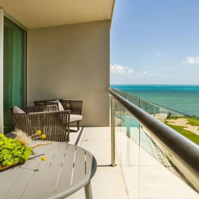Corner balcony suite with seating area and ocean view overlooking golf course and coastline.