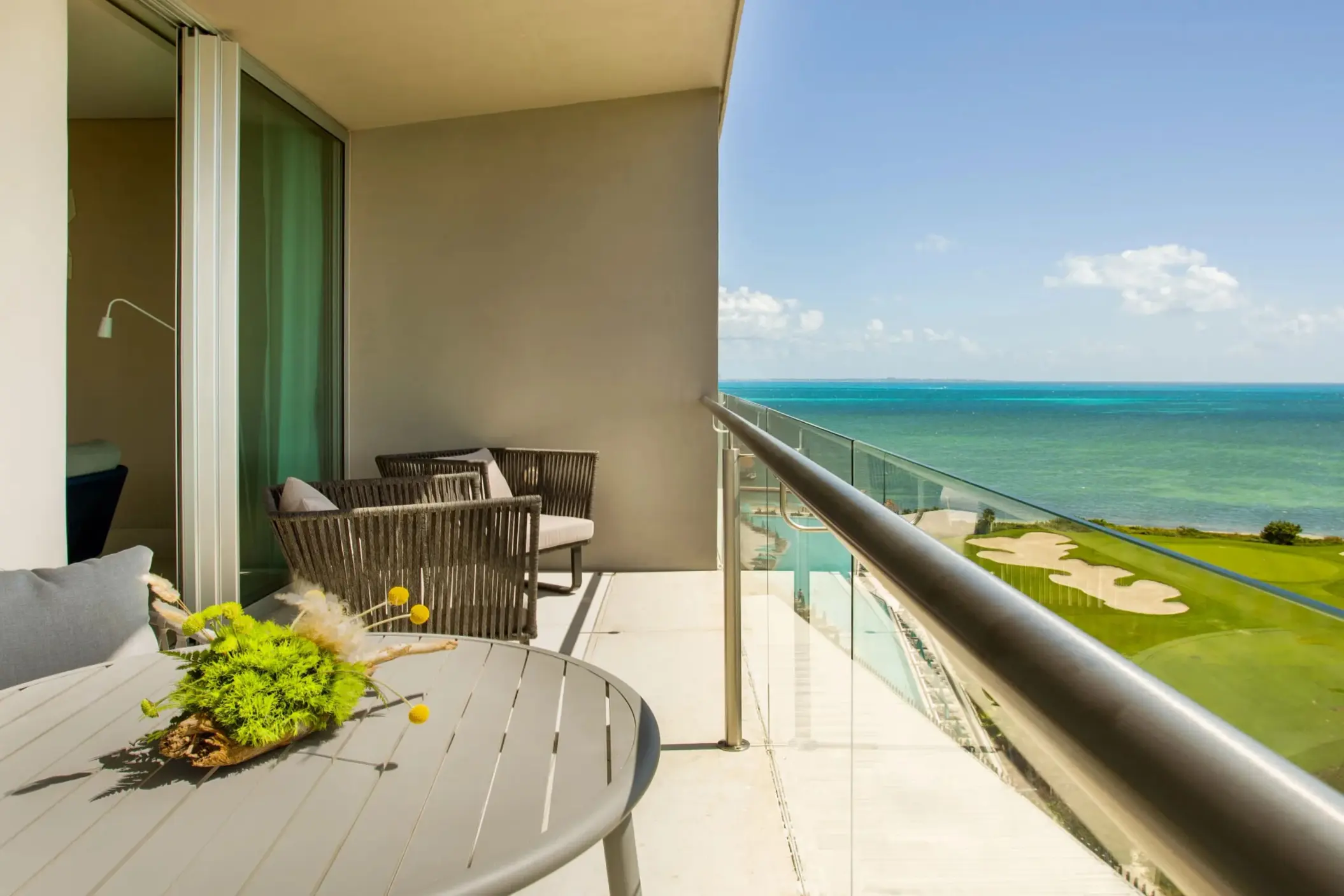 Corner balcony suite with seating area and ocean view overlooking golf course and coastline.