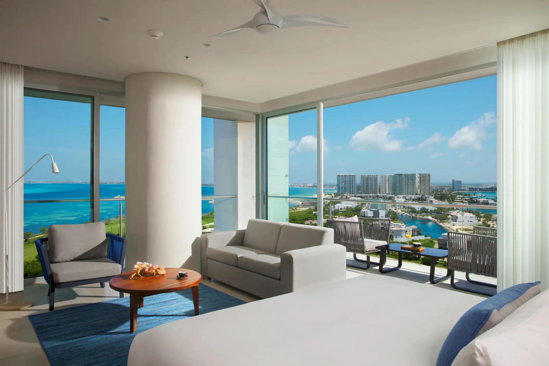 Corner ocean view room with panoramic windows and king bed facing the turquoise water.