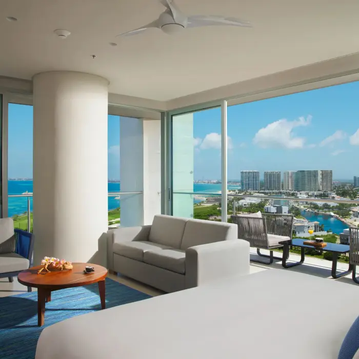 Corner ocean view room with panoramic windows and king bed facing the turquoise water.