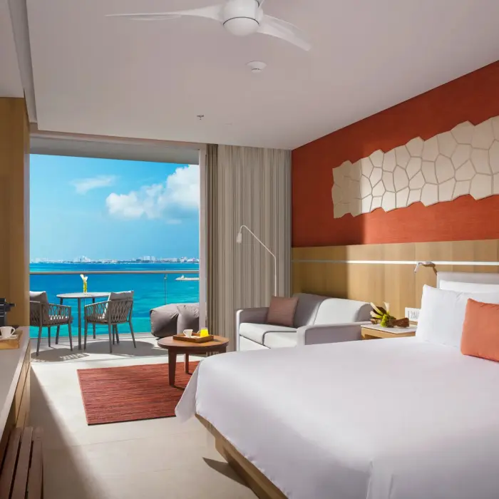 Deluxe ocean view room with king bed, sofa, and balcony overlooking the Caribbean Sea.