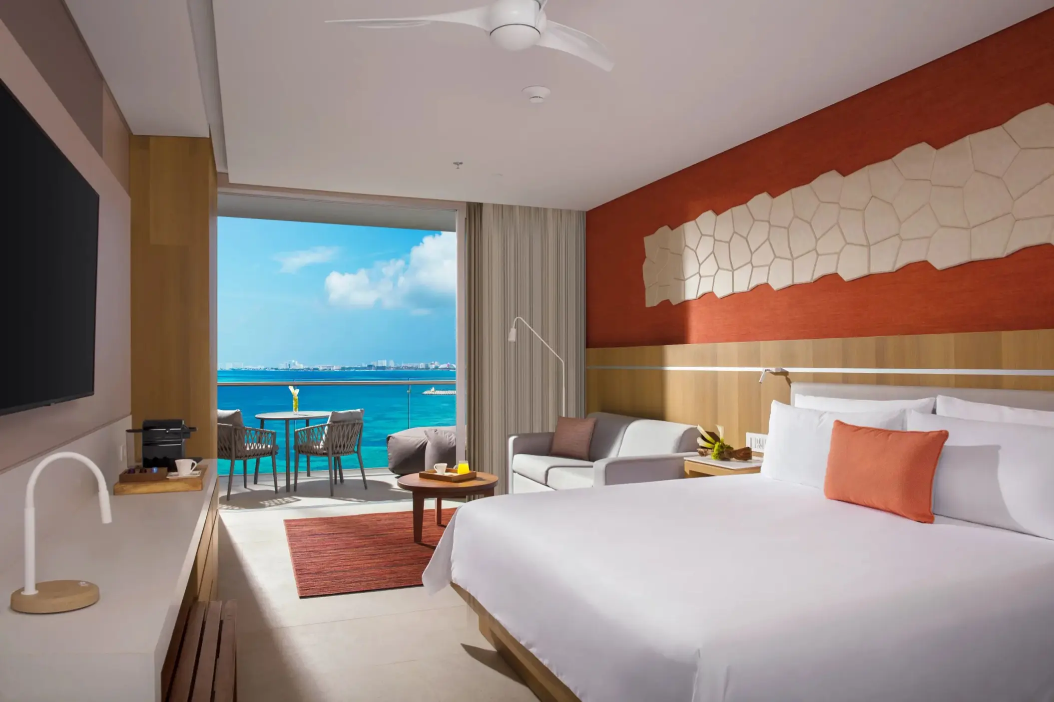 Deluxe ocean view room with king bed, sofa, and balcony overlooking the Caribbean Sea.