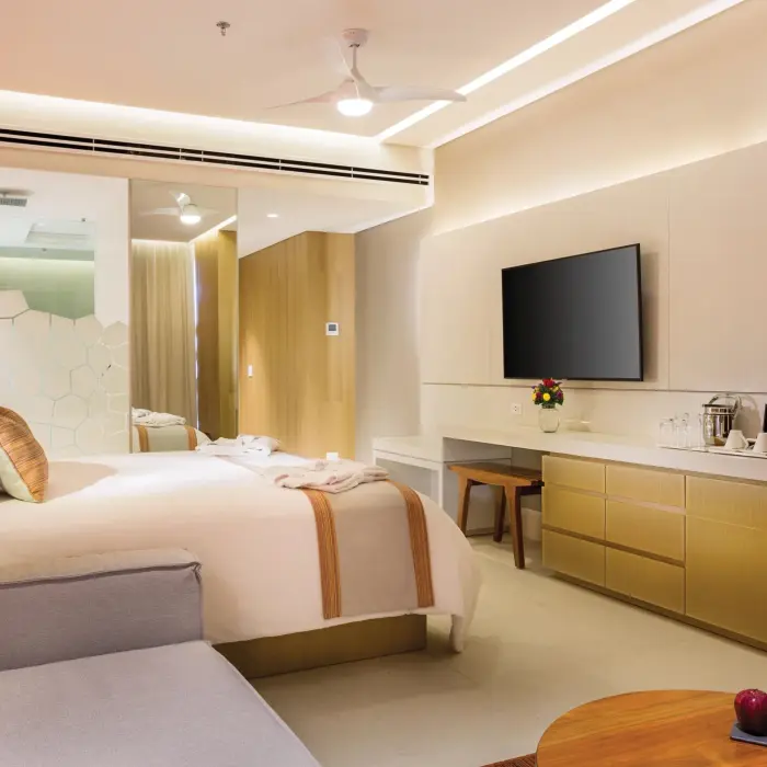 Deluxe ocean view room with king bed, sleek furnishings, and balcony seating overlooking crystal-clear waters.